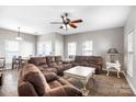 Spacious living room with plush brown sectional, ceiling fan, and windows for natural light at 12419 Swan Wings Pl, Huntersville, NC 28078