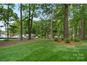Picturesque backyard with lush green lawn, mature trees, and serene lake views from the property at 147 Pearl Bay Dr, New London, NC 28127