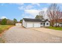 This home features a two-car garage, a long gravel driveway, and a storage building at 155 Country Ln, Mooresville, NC 28115