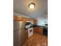 Efficient kitchen with stainless steel refrigerator, white appliances, and wood cabinets at 9130 Charminster Ct, Charlotte, NC 28269