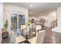 Bright dining room with glass table, leading into a modern white kitchen and staircase at 1004 Whipcord Dr, Waxhaw, NC 28173