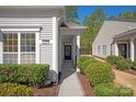 View of the home's entrance, featuring manicured bushes, a small front porch, and a black front door at 1005 Sweetleaf Dr, Fort Mill, SC 29707