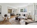 Bright living room featuring a modern sofa, neutral tones, hardwood floors, and an open layout to the dining area at 1749 Archdale Dr, Charlotte, NC 28210