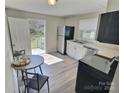 Kitchen with stainless steel appliances, white cabinets, access door to back yard, and new wood floors at 507 E Maple Ave, Gastonia, NC 28054