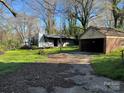 View of the backyard revealing a detached garage and shed, framed by lush green grass and surrounding trees at 521 Pee Dee Ave, Albemarle, NC 28001