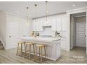 Bright kitchen with a spacious island, pendant lights, white cabinetry, and stainless steel appliances at 8947 Nettleton Ave, Charlotte, NC 28215