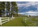 Green pasture enclosed by white fencing, with trees and power lines in the background at 11215 Idlewild Rd, Matthews, NC 28105