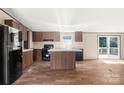 Bright kitchen with wood cabinets, island, and black appliances, offering a functional cooking space at 141 Lakewind Dr, Mooresville, NC 28115