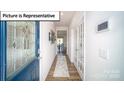 Bright hallway featuring hardwood floors, white walls, and a decorative front door with glass detail at 3018 Sassafras Trl, Gastonia, NC 28056