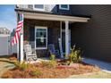 The cozy front porch has rocking chairs, an American flag, and decorative landscaping for a welcoming feel at 446 Brannon Meadows Dr, York, SC 29745