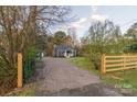 View of the charming blue cottage, shed, mature tree, and gravel driveway at 6282 Richburg Rd, Great Falls, SC 29055