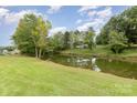 Beautiful backyard featuring lush green grass and mature trees along the water's edge at 7790 Blackwood Rd, Denver, NC 28037