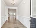 Inviting foyer with wood flooring, white wainscoting, and a view into the open-concept living area at 9650 Liberty Hill Dr, Mint Hill, NC 28227