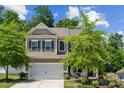 Charming two-story home features a white garage door, a manicured lawn, and lush landscaping at 117 Cramerton Mills Pkwy, Cramerton, NC 28032