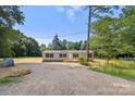 Quaint home with gravel driveway situated on a spacious lot surrounded by mature trees and nature at 143 Lakewind Dr, Mooresville, NC 28115