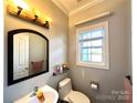 Cozy half bathroom featuring a window, toilet, and mirror at 12217 Greymore Ct, Charlotte, NC 28277