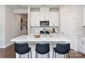 Modern white kitchen with a center island, stainless steel appliances, and bar stool seating at 142 Shepherds Landing Dr, Mooresville, NC 28115