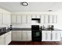 Well-lit kitchen featuring white cabinets, black appliances, and tile backsplash for modern charm at 269 Loch Stone St, Fort Mill, SC 29715