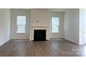 Cozy living room with a fireplace, large windows for natural light, and hardwood flooring at 324 Basil Dr, Indian Trail, NC 28079