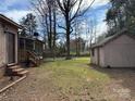 View of backyard showing home's enclosed porch, outbuildings, and lush greenery at 8609 William Wiley Dr, Charlotte, NC 28215