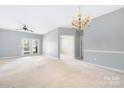 Bright, carpeted living room featuring French doors, chandelier, and neutral paint, offering a calming space at 16312 Redstone Mountain Ln, Charlotte, NC 28277