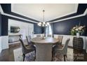 Stylish dining room featuring dark blue walls, wooden table, chandelier, and wainscoting at 9762 Verdun Ct, Indian Land, SC 29707