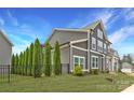 Modern home with gray siding, white trim, a row of mature trees and a black metal fence at 11327 James Coy Rd, Davidson, NC 28036
