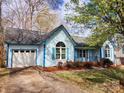 View of a charming light-blue home with white garage door, arched window and well-kept lawn at 121 Deertrack Dr, Mount Holly, NC 28120
