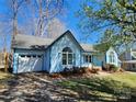 View of a charming light-blue home with white garage door, arched window and well-kept lawn at 121 Deertrack Dr, Mount Holly, NC 28120