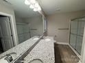 Bathroom featuring double sinks with granite countertops, framed mirror, and a glass-enclosed shower at 1309 Meadow Ave, Kannapolis, NC 28083