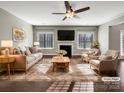 Bright living room featuring a fireplace, a ceiling fan, hardwood floors, and neutral decor at 15827 Arabian Mews Ln, Charlotte, NC 28278