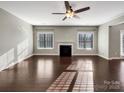 Bright living room featuring a fireplace, a ceiling fan, hardwood floors, and windows providing natural light at 15827 Arabian Mews Ln, Charlotte, NC 28278
