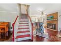 View of the staircase with red accents, leading to a living area with a fireplace and comfortable seating at 207 Crossing Ave, Belmont, NC 28012