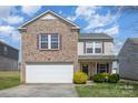 Charming two-story home featuring a brick facade, attached garage, and well-manicured lawn at 504 Zander Woods Ct, Mount Holly, NC 28120
