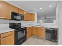 The kitchen features black appliances, wooden cabinets, and tile flooring, with a view into the living room at 7707 Petrea Ln, Charlotte, NC 28227