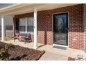 Close-up of a home's brick front porch with white columns, bench seating, and decorative front door at 1017 Village Green Ln, Rock Hill, SC 29730