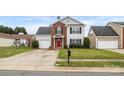 Charming two-story home featuring a red front door, brick accents, green lawn, and attached garage at 4917 Spruce Peak Rd, Charlotte, NC 28278