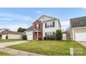 Charming two-story home featuring a red front door, brick accents, green lawn, and attached garage at 4917 Spruce Peak Rd, Charlotte, NC 28278