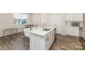 Bright kitchen island features white cabinetry, stainless sink and seating at 6048 Chelsea Oaks Rdg, Tega Cay, SC 29708