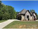 Side view of the house showing the driveway and garage, with stone and brick accents and mature landscaping at 1021 Mccollum Oaks Ln, Monroe, NC 28110
