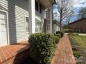 Close-up of a home's exterior showing a brick walkway bordered by lush, green shrubbery at 1968 12Th Street Ne Pl, Hickory, NC 28601