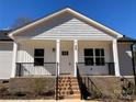 Inviting covered porch with brick base, decorative railings and a prominent front door at 2037 Powerline Dr, Gastonia, NC 28054
