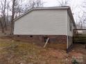 Mobile home exterior showcases a brick foundation, vinyl siding, and basement access at 2130 Babbling Brook Ln, Gastonia, NC 28052