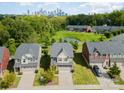 Aerial view of a home situated near a pond, surrounded by lush greenery and with the city skyline in the distance at 3614 Dolly Madison Rd, Charlotte, NC 28208