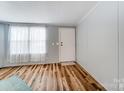 Bright living room with wood floors, white door, and large window with curtain brings ample natural light at 405 Briarwood Ct, Mount Holly, NC 28120
