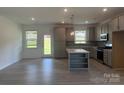 Open-concept kitchen with gray cabinets, island, stainless steel appliances, and natural light at 411 Sunharvest Ln, Indian Trail, NC 28079