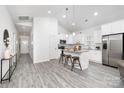 Bright kitchen with white cabinetry, stainless steel appliances, an island with bar stools, and hardwood-style floors at 5824 Patton St, Charlotte, NC 28269