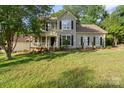 Traditional-style home with a welcoming front porch, dark shutters and a well-maintained front lawn at 6210 Skyline Dr, Charlotte, NC 28269