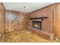 Cozy living room featuring a brick fireplace, wood paneling, neutral carpet, and chandelier at 624 Flicker St, Concord, NC 28027