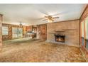 Comfortable living room featuring wood paneling, brick fireplace, ceiling fan, and an open floorplan connecting to the kitchen at 624 Flicker St, Concord, NC 28027